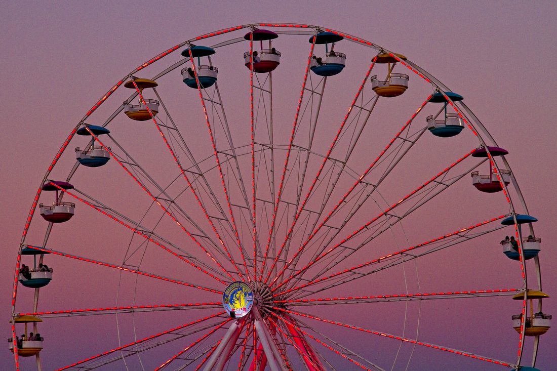 Carnival ferris wheel silhouetted against a gradient purple twilight sky