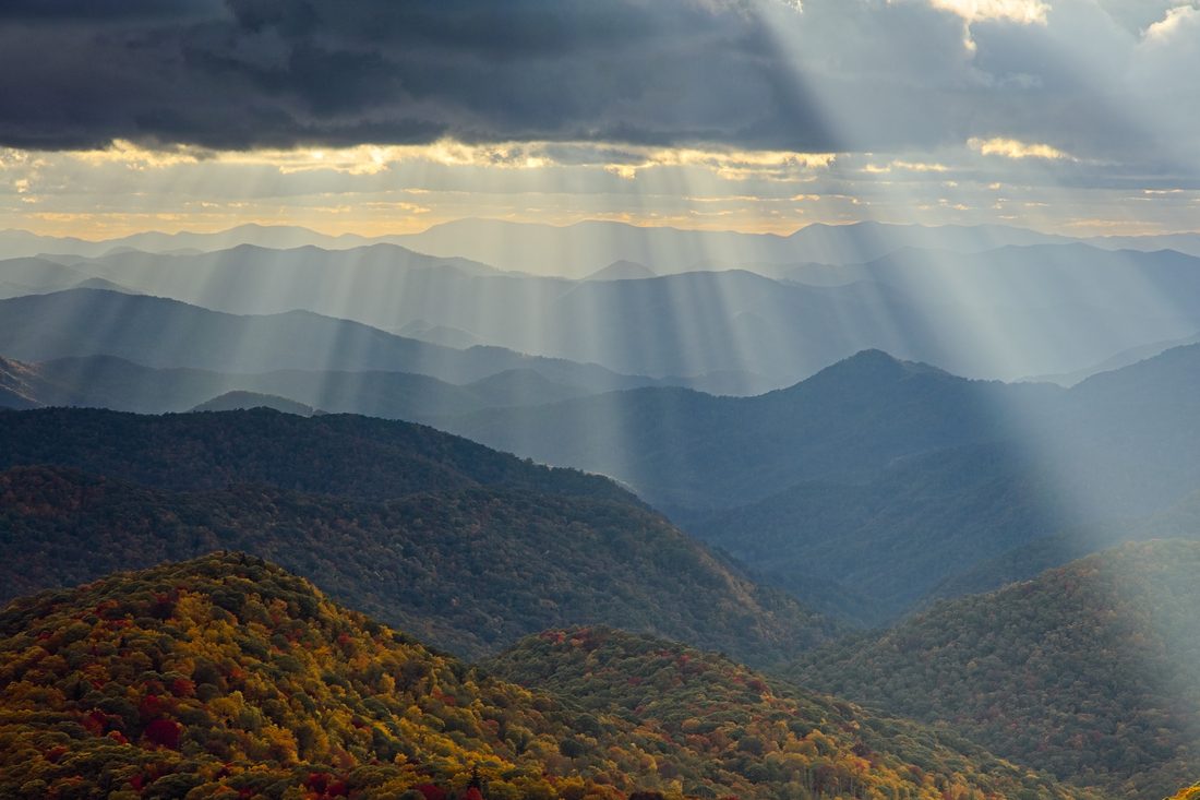 Layered Blue Ridge summits with golden god rays raking across autumn ridges at sunset