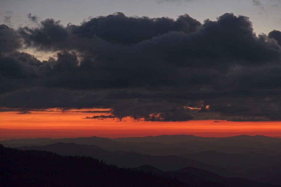 Molten red horizon under dramatic cloud bands at sunset over the Blue Ridge