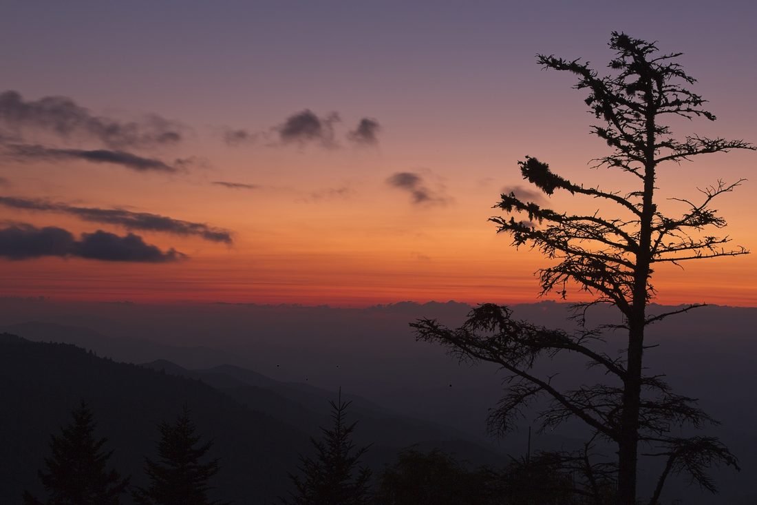 Pre-dawn sunrise breaking gold over silhouetted mountain ridges